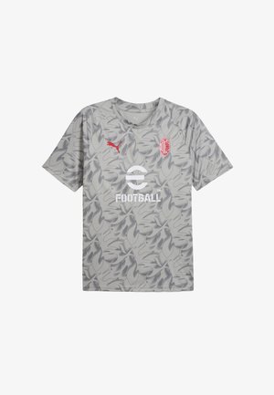 T-shirt gris clair avec un motif camouflage, logo Puma en rouge et un graphisme "FOOTBALL" en blanc. Manches courtes et design col ras du cou.