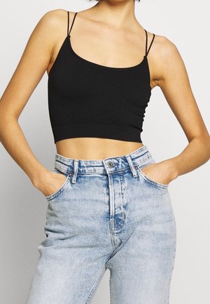 Top corto a costine nero con spalline sottili, abbinato a jeans in denim azzurro chiaro a vita alta con una finitura sbiadita e tasche anteriori.