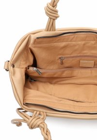 Borsa in pelle color cuoio con manico annodato. Internamente è dotata di diverse tasche, tra cui un scomparto con zip, e una fodera in tessuto liscia.