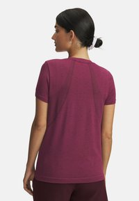 Short-sleeve maroon athletic shirt, textured fabric with subtle pattern, curved yoke seam detail on back, round neckline, relaxed fit.