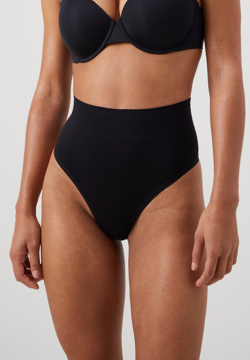 High-waisted black underwear made from smooth fabric, featuring a seamless design and a subtle waistband for comfort and fit.