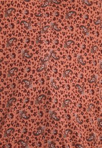 Stofftextil mit orangefarbenem Hintergrund und Paisleymuster in Dunkelrot, Blau und weißen floralen Akzenten. Weiche, strukturierte Oberfläche.