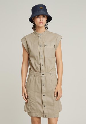 Khaki lnian dress w krótkich rękawach, z guzikami z przodu i kieszenią na piersi. Połączony z granatowym kapeluszem typu bucket z naszywką z logo.