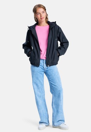 Black lightweight jacket with hood, elastic cuffs, and front zipper, paired with a pink shirt and light blue flared jeans. White sneakers.