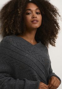 Maglione grigio lavorato a maglia con scollatura a V e motivo a coste diagonali con dettagli a traforo. Texture morbida e vestibilità rilassata.