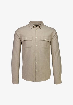 Camisa de manga larga beige hecha de una tela suave, con frente abotonado, dos bolsillos en el pecho y un cuello clásico.