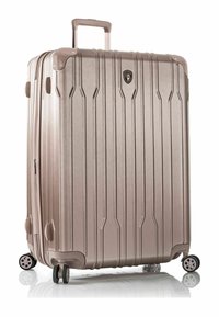 Valigia rigida in oro rosa metallizzato, con scanalature verticali, manico retraibile e quattro ruote multidirezionali.