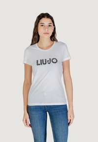 T-shirt bianco in cotone con logo "LIU•JO" nero a motivo sul davanti. Maniche corte e scollatura rotonda, abbinato a jeans blu.