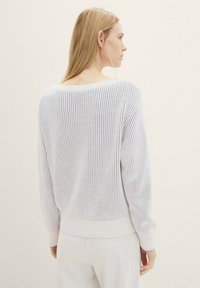 Hellgrauer gerippter Pullover mit weitem Rundhalsausschnitt und langen Ärmeln. Die Textur ist weich, mit einem eng anliegenden Saum an der Taille.