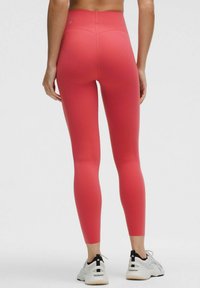 Leggings de înălțime mare, într-o nuanță vibrantă de roz, realizate dintr-un material elastic și neted. Prezintă o croială ajustată și un logo aproape de talie.