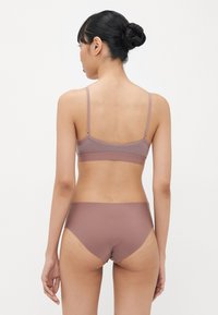 Mjuk, elastisk, ljusbrun bralette och matchande bikini, med justerbara remmar och sömlös design för komfort och passform.