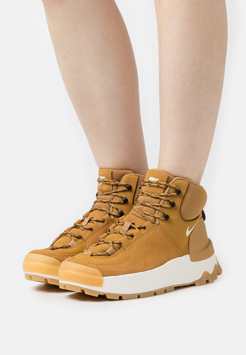 Bruine hoge sneakers van textuur-suède, met een rubberen zool en zwarte accenten. Heeft een vetersysteem en een gewatteerde kraag voor extra ondersteuning.