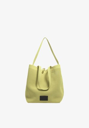 Sac fourre-tout en maille jaune avec des anses en tissu doubles et un accent de label noir. Texture douce, large ouverture et design spacieux pour une utilisation polyvalente.