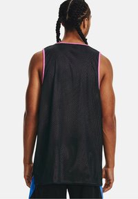 Muž s copánky, oblečený v černé síťované bezkraťové sportovní dresu s růžovými detaily, zobrazený zezadu na jednobarevném pozadí.