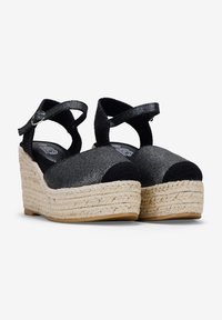 Espadrilles compensées noires et grises avec tissu tissé, bout rond et bride à la cheville. Présente une semelle intermédiaire en jute et une semelle en caoutchouc.