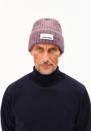 Paarse gebreide beanie met een ribbelstructuur en een platte label met de tekst "ARMEDANGELS." Gecombineerd met een donkere coltrui.