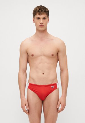 Rote Schwimmslips aus glattem, dehnbarem Material mit weißen seitlichen Akzenten und Logodetails. Entworfen für eine enganliegende Passform.