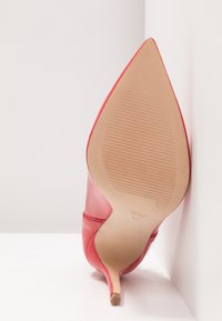 Chaussure à talon stiletto à bout pointu en cuir rouge vue de la semelle, montrant la semelle beige texturée et la taille 37.