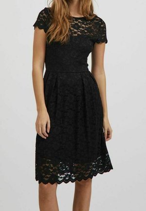 Czarna koronkowa sukienka z krótkimi rękawami, dopasowanym górnym częścią i rozkloszowanym dołem z falistym brzegiem. Całość zdobiona teksturowanym kwiatowym wzorem.