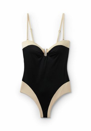 Schwarz-beiger Einteiler mit verstellbaren dünnen Trägern und einem goldfarbenen Reißverschlussdetail vorne in der Mitte der Brust.