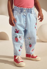 Šviesiai mėlynos dryžuotos džinsinės kelnės su elastinga juosmens juosta, dekoruotos siuvinėtomis braškėmis ir gėlėmis. Derinamos su raudonais aukštakulniais sportbačiais.