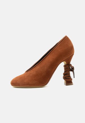 Brun ruskind højhælet sko med en skulptureret hæl indpakket i matchende læderremme og en lille spændedetalje.