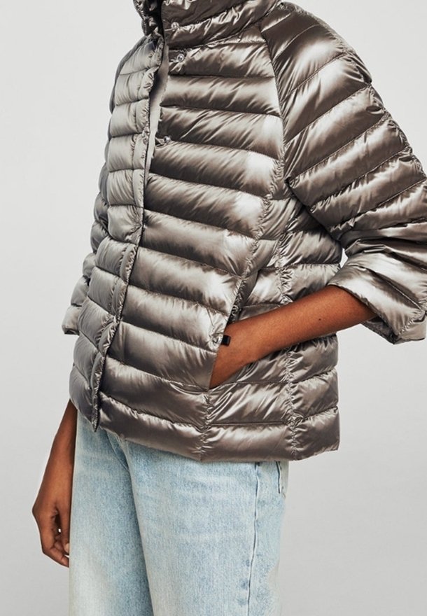 Toppatakki metallinhohtoisessa harmaassa, vaakasuorilla toppauksilla, lyhyillä hihoilla ja pystykauluksella. Takissa on edestä suljettava vetoketju ja sivutaskut.