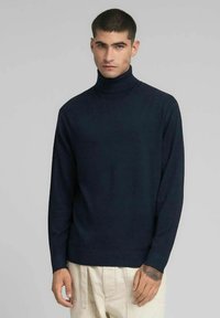Maglione dolcevita blu navy realizzato in morbido tessuto a maglia. Caratterizzato da maniche lunghe, silhouette aderente e ricamo discreto del logo sul petto.