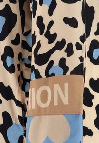 Blusa de satén con base beige y estampado de leopardo en negro y azul claro, y una banda marrón con la palabra "FASHION" en texto blanco en negrita.