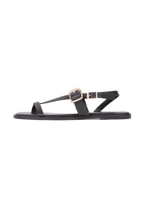 Black flat sandals made of smooth material, featuring thin straps and a rectangular gold buckle detail. Sleek design and open-toe style.