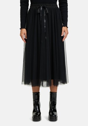 Black tulle skirt with a wide waistband, featuring a satin drawstring. Paired with glossy black platform boots for contrast.