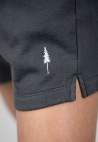 Dark gray athletic shorts made of cotton, featuring a white embroidered tree logo and side slits at the hem for ease of movement.