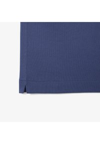 Tessuto testurizzato blu navy con orlo dritto e spacchi laterali. Sfondi a quadrati visibili, che evidenziano il design del materiale traspirante.