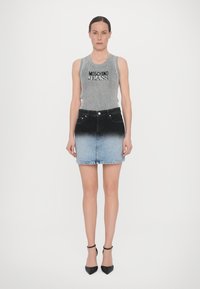 Pelēka ribota bez piedurknēm ar "Moschino Jeans" logo, apvienota ar džinsa svārkiem ar ombrē tonējumu no melna līdz gaiši zils. Melni augstpapēžu kurpes.