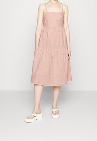 Raidoitu midi-mekko punaisena ja valkoisena, jossa on neliönmuotoinen pääntie, ohuet hihnat ja kerätty hameosa. Yhdistetty valkoisiin platform-sandaaleihin.