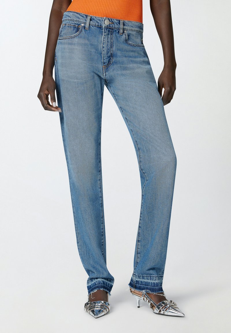 Jeans rectos de color azul claro, hechos de denim con un acabado desgastado, con diseño de cinco bolsillos y un dobladillo sin terminar en los puños.