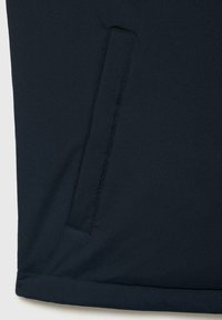Donkerblauwe jas van gladde stof, met een zijzak en een rechte zoom. Het ontwerp is minimalistisch met strakke lijnen.