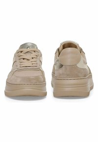 Beige lenkkarit, joissa on mikrokuitu- ja nahkatekstuureja, metallikoristeita, pehmustettu pohja ja tekstuuritettu kumiosa ulkopohjassa.