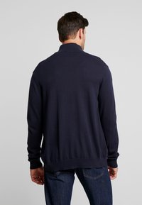 Mörkblå långärmad cardigan i ett slätt stickat tyg, med ribbad krage och manschetter, samt en åtsittande midja utan synliga mönster.