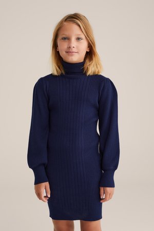 Mornarska haljina od rebrastog pletiva s visokim turtleneck-om, dugim nabranim rukavima i prilagođenim oblikom. Tekstuirano tkivo naglašava dizajn.