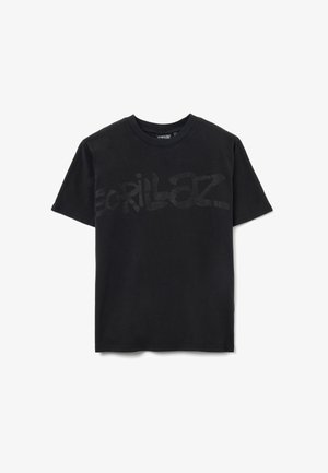 Camiseta de algodón negra con un gran logo "Gorillaz" semi-transparente en la parte delantera. Cuello redondo estándar y mangas cortas, textura suave.