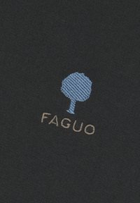 Tessuto scuro con un logo di un albero blu ricamato sopra il testo "FAGUO" in beige. La texture appare liscia e leggermente strutturata.