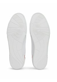 Zapatillas blancas con una suela de goma texturizada que presenta un diseño circular y "TOMMY HILFIGER" grabado en el lateral. Diseño superior simple y suave.