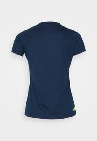 T-paita tummansinisestä lyhythihaisesta kankaasta, jossa on pyöreä kaula-aukko ja vihreä logo-aksentti helman kohdalla. Valmistettu pehmeästä, kevyestä kankaasta, jossa on sileä pinta.