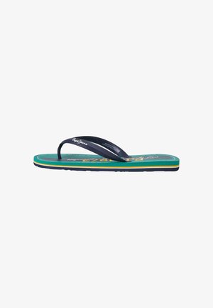 Tongs avec une semelle en teal ornée de rayures jaunes et navy, des sangles en caoutchouc noires et un logo imprimé sur la sangle et la semelle.