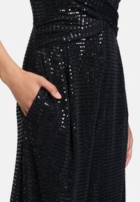 Czarna sukienka z cekinami o fakturowanej powierzchni, z eleganckim krojem, boczną kieszenią i dopasowaną talią.