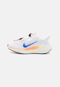 Białe buty sportowe z fakturowaną cholewką, niebieskim logo Nike, pomarańczowymi akcentami i amortyzowaną podeszwą. Posiadają system sznurowania z regulowanym zapięciem.