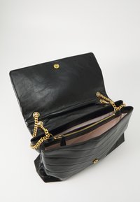 Black leather handbag with a quilted design, gold-tone hardware, chain strap, and a pink interior. Features a magnetic closure and zip pocket.