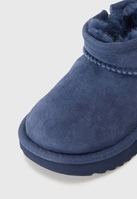 Bottine en suède bleu avec doublure douce, bout rond, tige texturée et accents cousus. Semelle légère avec une finition lisse.