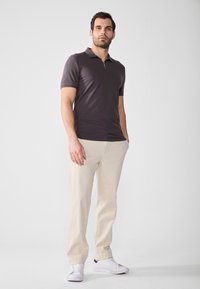 Dark grey short-sleeve polo shirt with a zip collar, paired with light beige slacks and white sneakers, featuring a smooth fabric texture.